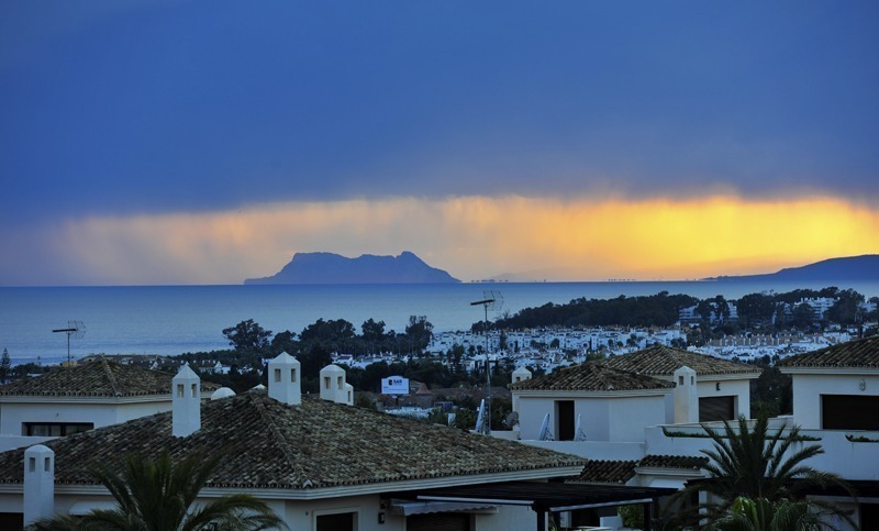 Een regebui trekt over de Costa del Sol gezien vanaf Nueva Andalucia Marbella by Costas & Casas